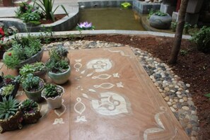 A garden area with a patterned walkway, potted plants, and a small water feature. - Gudao Gudao Renjia Inn (Lijiang)