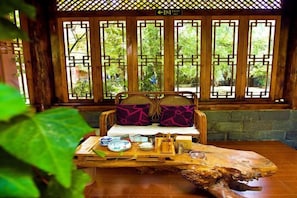 Una habitación tradicional con un banco de madera, cojines y una mesa con juego de té.