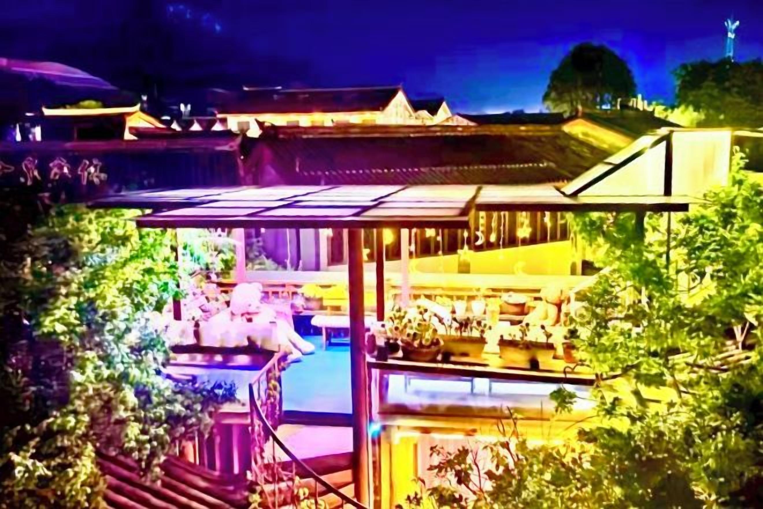 A traditional Japanese-style building with a covered outdoor area, a pool, and lush greenery.