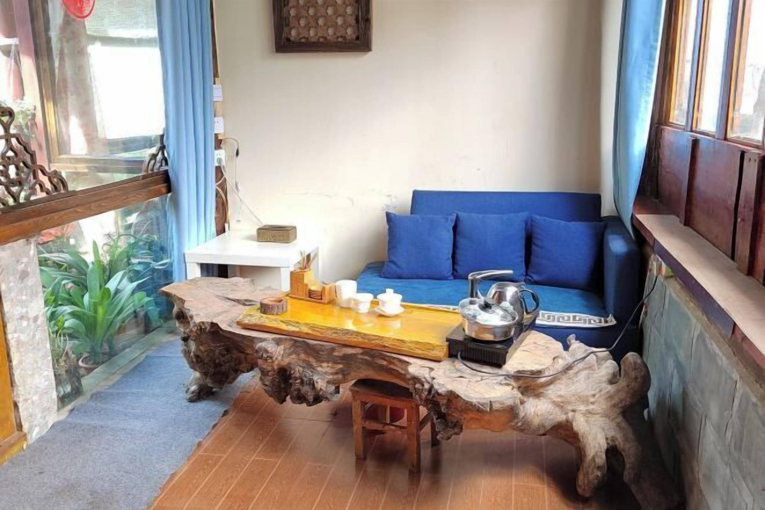 Una sala de estar con un sofá azul, una mesa de centro de madera y una mesita con tazas y una tetera.