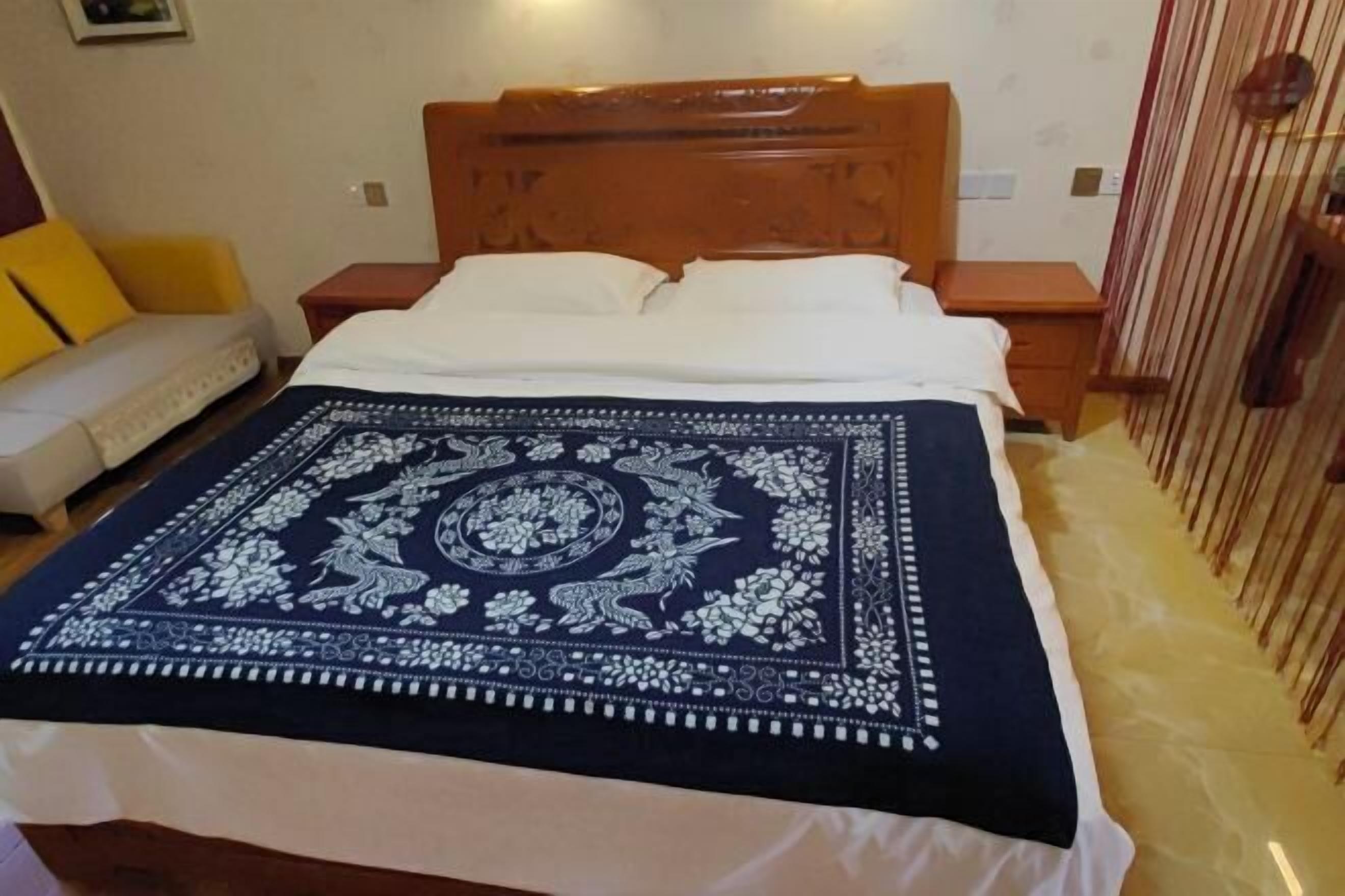 A bed with a patterned blanket, a wooden headboard, and a bedside table with a lamp.