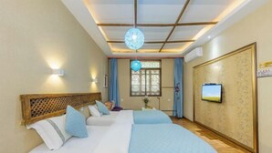 A hotel room with a large bed, a television, and a decorative ceiling light. - Gudao Gudao Renjia Inn (Lijiang)