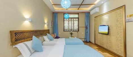 A hotel room with a large bed, a television, and a decorative ceiling light.