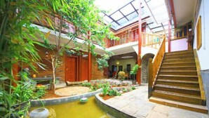 A multi-level atrium with a central garden, wooden staircase, and a glass ceiling. - Gudao Gudao Renjia Inn (Lijiang)