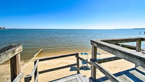 A wooden pier leading to a sandy beach with a clear blue sky.