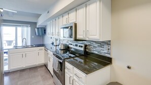 A modern kitchen with white cabinets, stainless steel appliances, and a granite countertop.