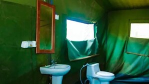 Et lille, grønt rum med en hvid vask, toilet og et spejl på væggen.