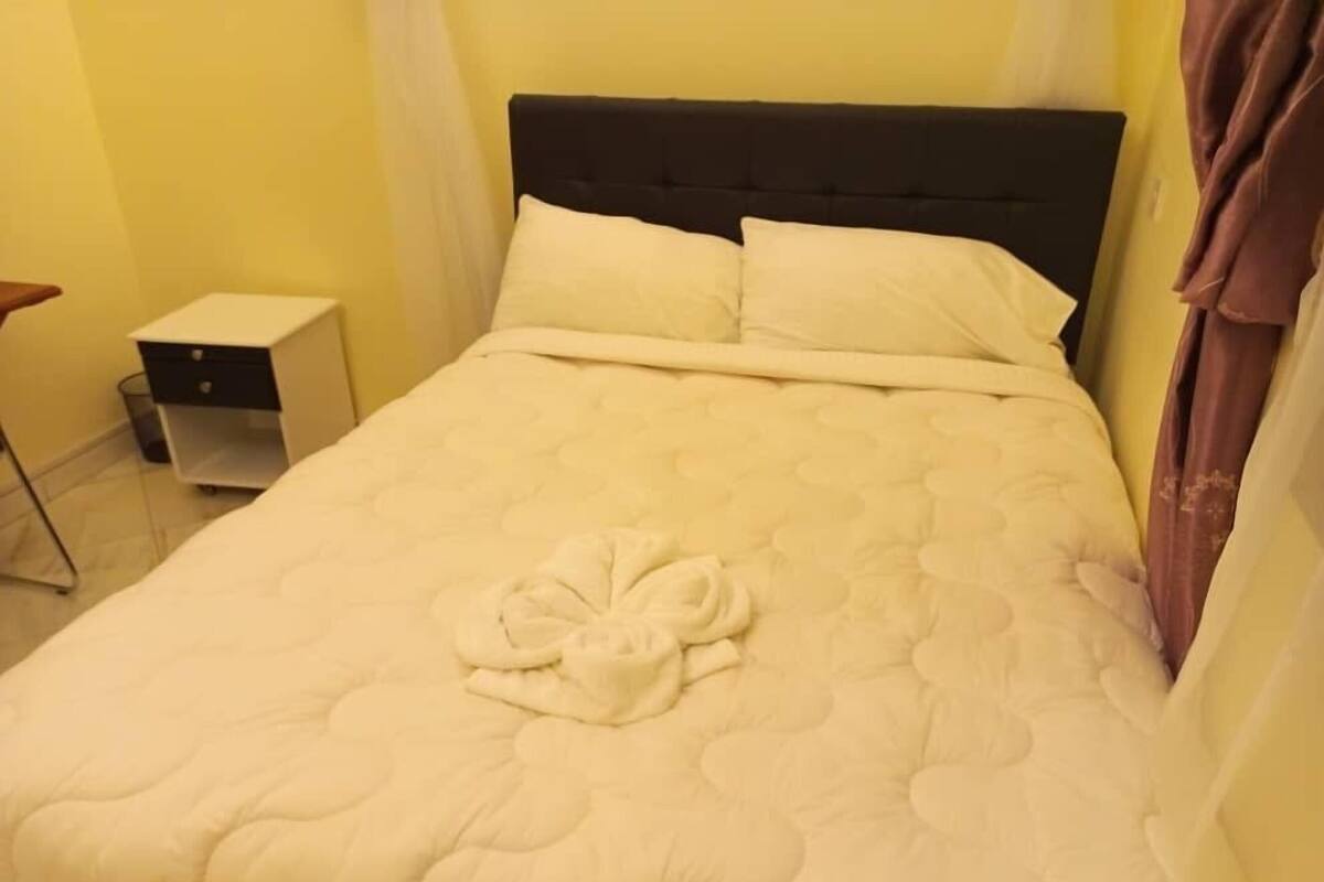 A bed with a quilted blanket, pillows, and a folded towel on it.