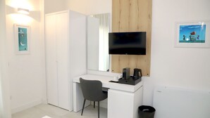 A modern room with a white desk, a chair, a flat-screen TV, a wooden panel, and a framed picture on the wall. - Lo Studio di viale Lo Re Camere & Caffè  (Lecce)