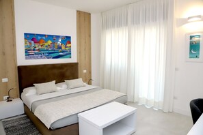 A bedroom with a bed, a bedside table, a nightstand, a painting, and a window with curtains. - Lo Studio di viale Lo Re Camere & Caffè  (Lecce)