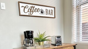 A kitchen with a coffee bar sign, a coffee maker, a toaster, and pots on a wooden cart. - Tower Grove Studio - Fenced Yard, W/D, Pet-Friendly - 4 Mi to Downtown (St. Louis)