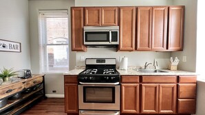 A kitchen with wooden cabinets, a stainless steel stove, a microwave, and a sink. - Tower Grove Studio - Fenced Yard, W/D, Pet-Friendly - 4 Mi to Downtown (St. Louis)