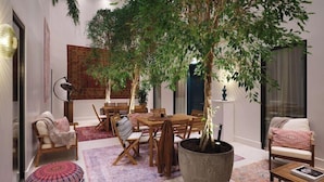A cozy dining area with a wooden table and chairs, surrounded by potted plants and a large tapestry. - The Other House South Kensington (London)