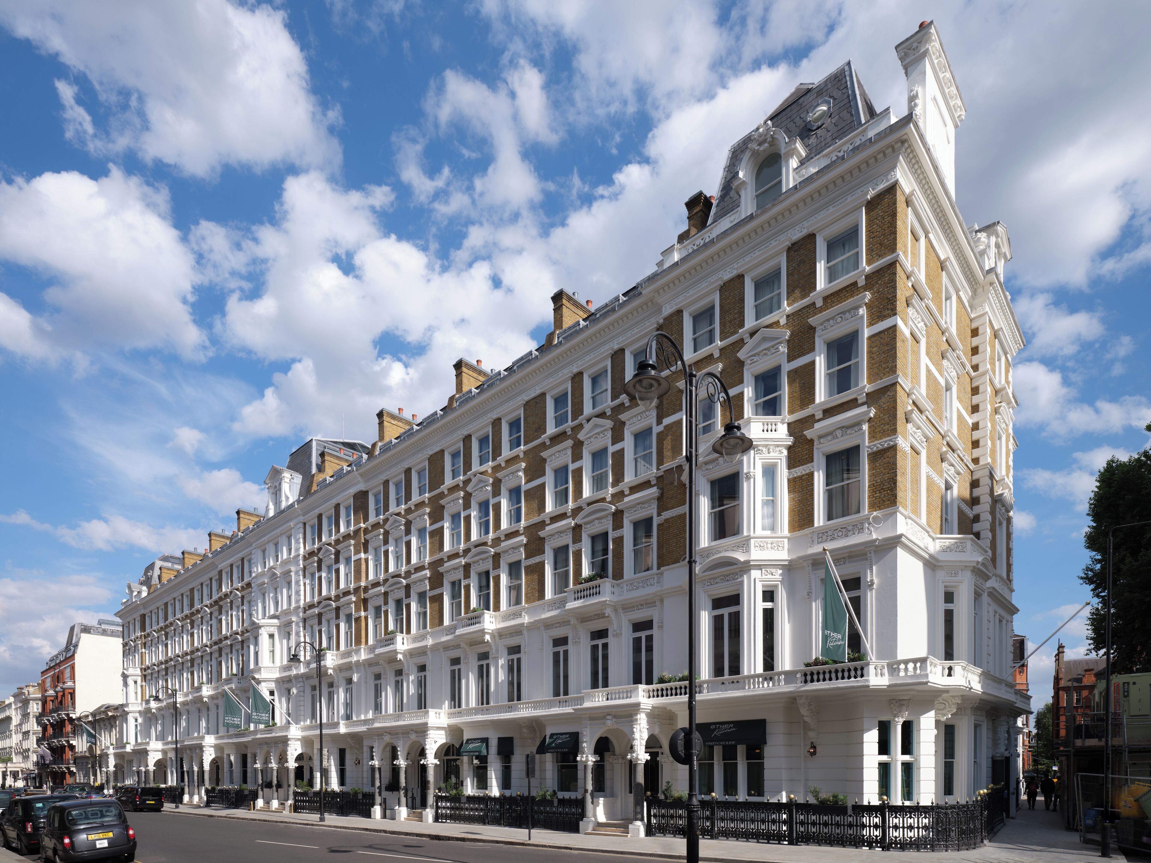A row of classic white buildings with uniform architecture, featuring multiple windows and a central entrance with a canopy.