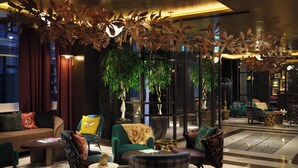 A modern lobby with a sofa, chairs, a coffee table, and a decorative ceiling. - The Other House South Kensington (London)