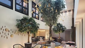 A spacious indoor area with seating arrangements, large windows, and decorative elements. - The Other House South Kensington (London)