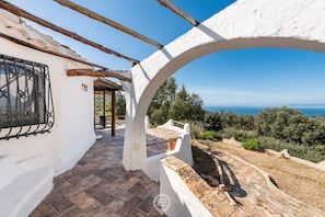 A white building with a tiled patio and a view of the sea. - Spectacular Seaview Escape (Quartu Sant'Elena)