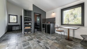 A modern kitchen with dark cabinetry, a built-in microwave, and a dining area with a table and chairs. - Spectacular Seaview Escape (Quartu Sant'Elena)