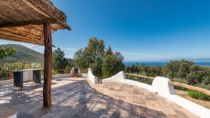 A terrace with a thatched roof, stone flooring, and white walls. - Spectacular Seaview Escape (Quartu Sant'Elena)