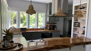 A modern kitchen with a wooden island, pendant lights, and a view of the outdoors.