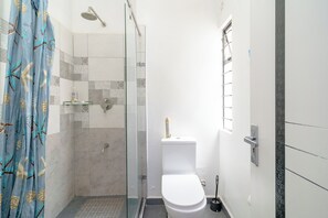 Een badkamer met een glazen douchecabine, een toilet en een douchegordijn met een patroon van zeedieren.