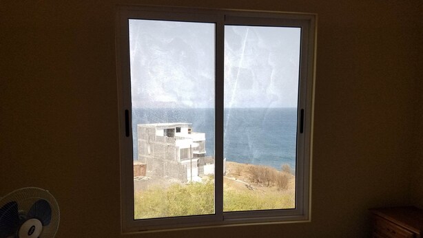Un dormitorio con un ventanal grande que da a un edificio y una masa de agua.