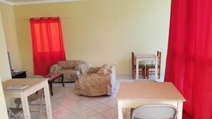 Una habitación con dos sofás, una mesa de comedor con sillas y una mesita con una silla.