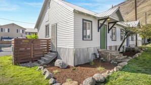 A small, single-story house with a sloped roof, a green door, and a small porch. - Salmon River Cabin #212 (Riggins)