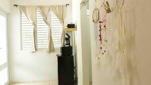 A room with a window, a desk with a computer, and a dreamcatcher on the wall.