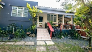 A modern house with a covered porch, a staircase, and a garden with various plants.