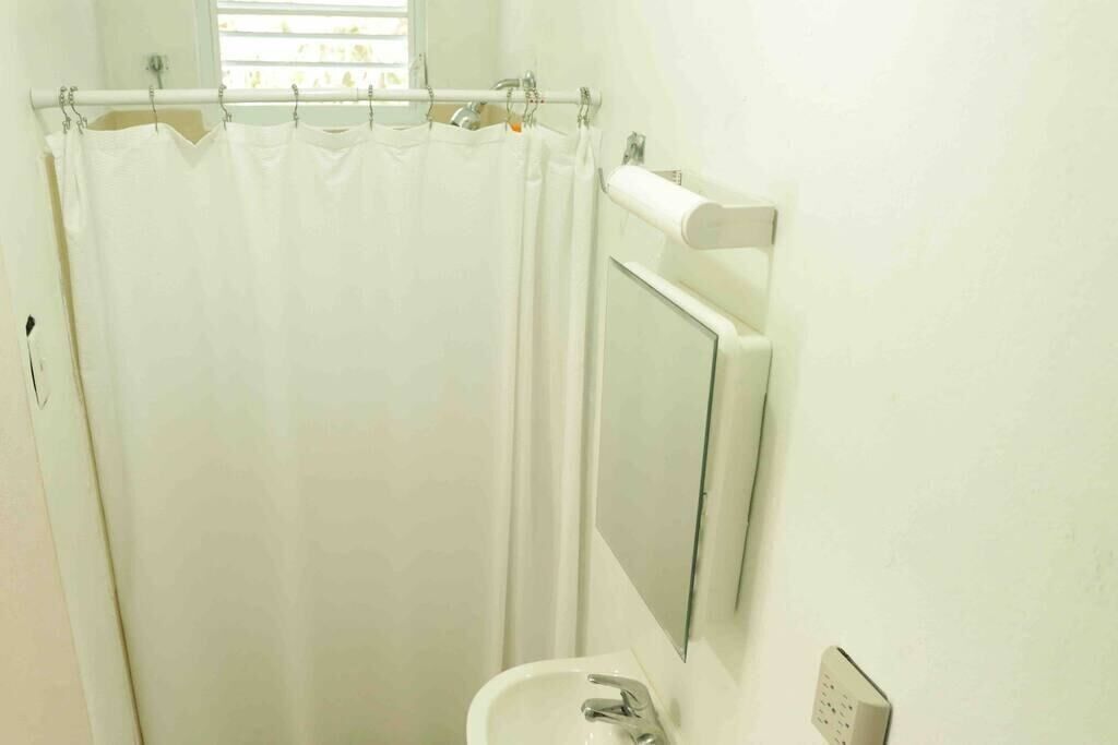 A bathroom with a shower curtain, a sink, a mirror, and a towel rack.