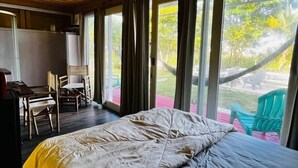 Ein Zimmer mit einem Bett, einem Schreibtisch und Stühlen. Große Fenster mit Vorhängen.