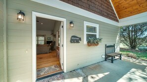 A house with a wooden porch, a welcome sign, and a bench. - Country Lane - Creek Front (Hiawassee)