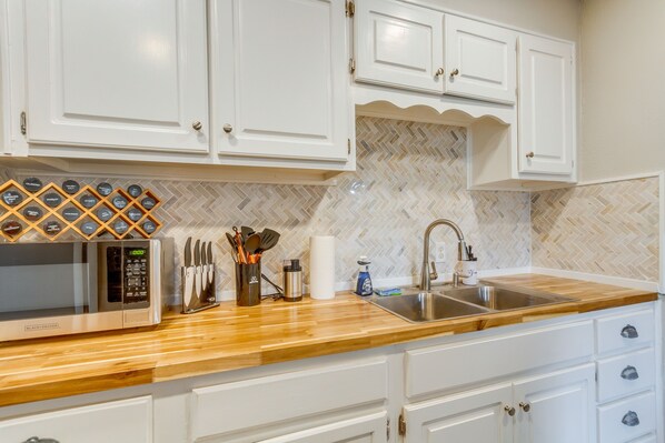 Kitchen features a stainless steel sink, microwave, and ample storage.