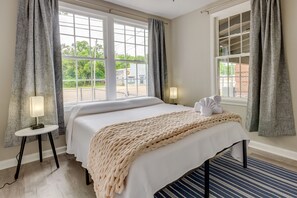 Relax in comfort with a large bed, flanked by two windows offering a view of the outdoors.