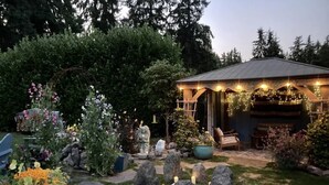Un jardín con un pabellón, un sendero de piedra y diversas plantas.