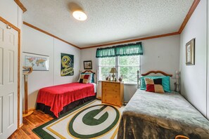 Quarto com duas camas, penteadeira, janela com cortinas, mapa na parede e um globo.