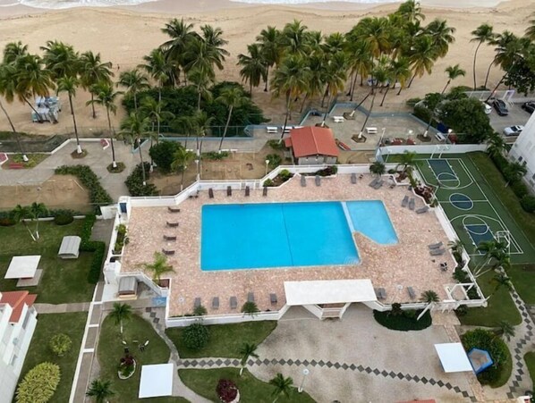 Ein Luftbild eines Resorts mit Swimmingpool, Palmen und Strand.