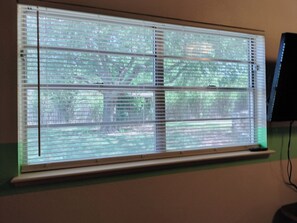 A window with horizontal blinds, a visible tree outside, and a monitor to the right. - Comanche, Cameron,  Good Year, Fort-Sill, Medicine Park, Lawton, Oklahoma. 
 (Lawton)