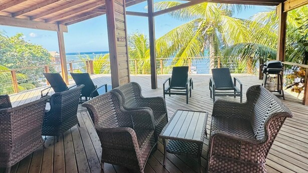 Een overdekt terras met rieten meubels en een plafondventilator.
