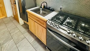 Een keuken met een roestvrijstalen fornuis, een spoelbak en een koelkast.