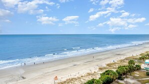 Una playa con cielo despejado, orilla de arena y algunas personas.