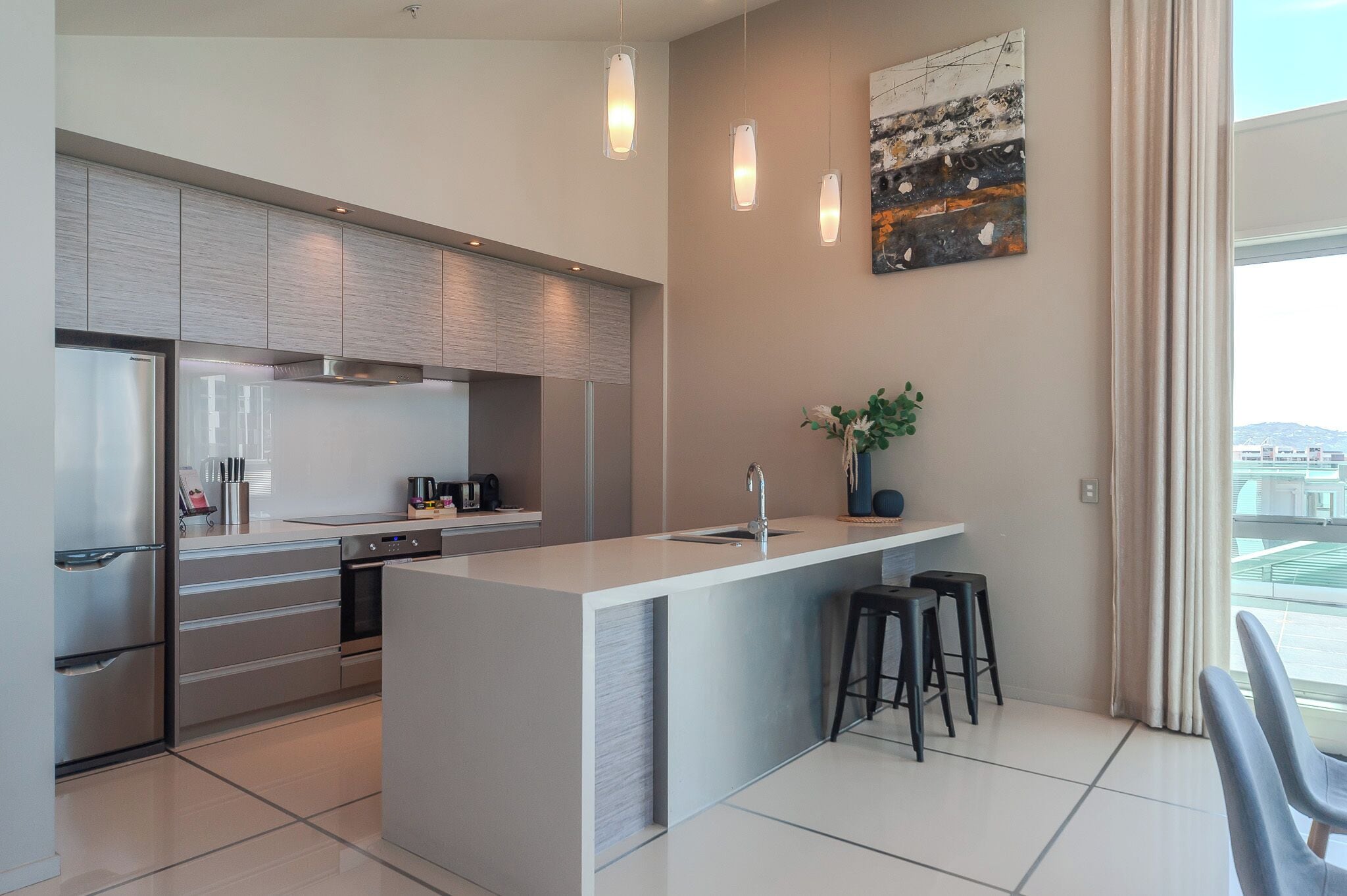 Una cocina moderna con una isla central, electrodomésticos de acero inoxidable y un amplio ventanal con vistas.