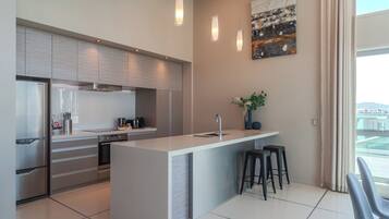 Una cocina moderna con una isla central, electrodomésticos de acero inoxidable y un amplio ventanal con vistas.