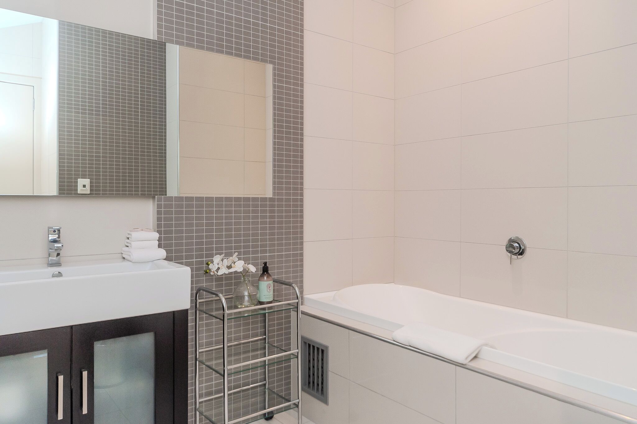 A modern bathroom with a white sink, a glass shower enclosure, and a large bathtub.