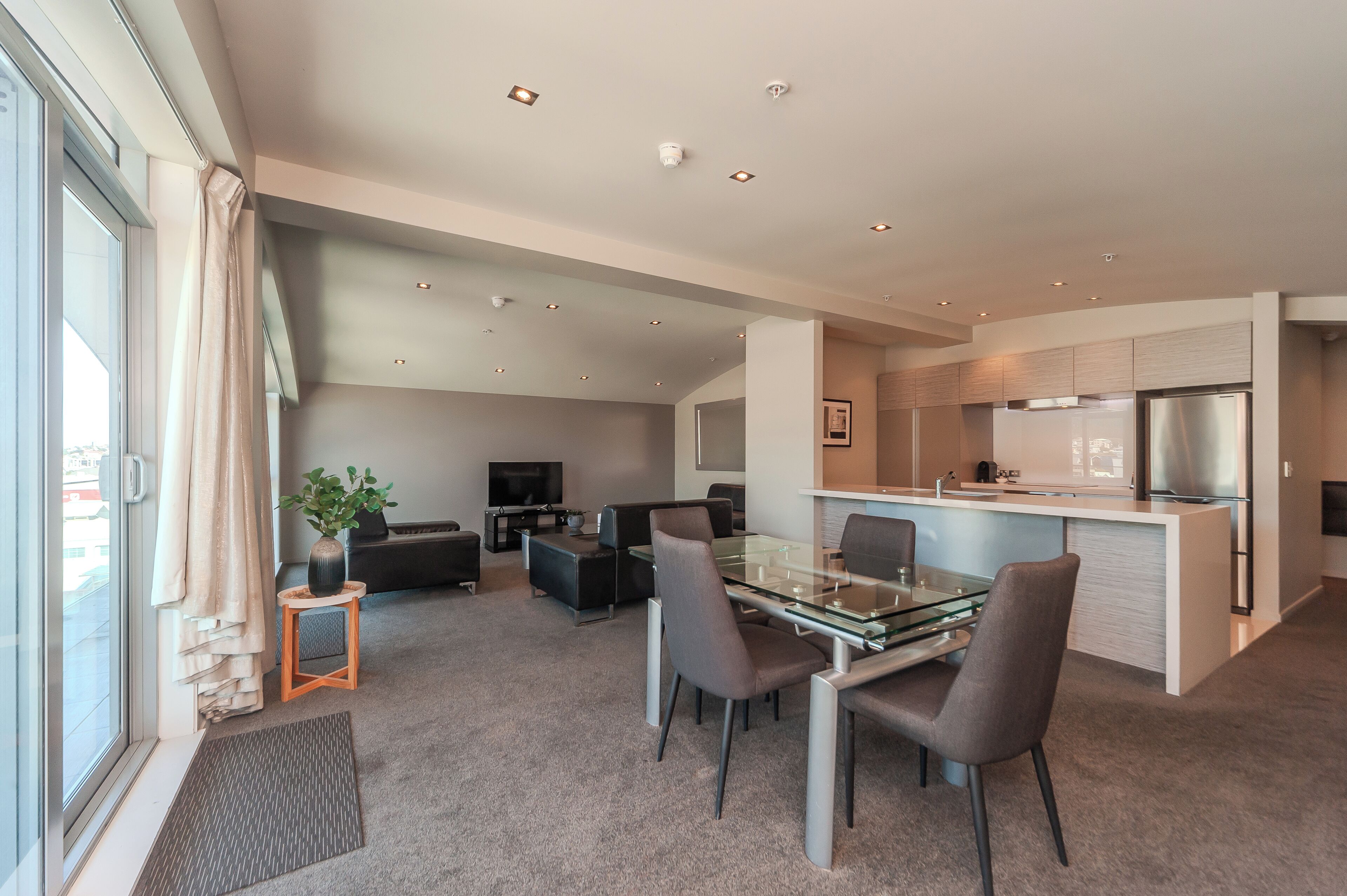A modern apartment with a dining area, kitchen, and living space.