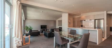 A modern apartment with a dining area, kitchen, and living space.
