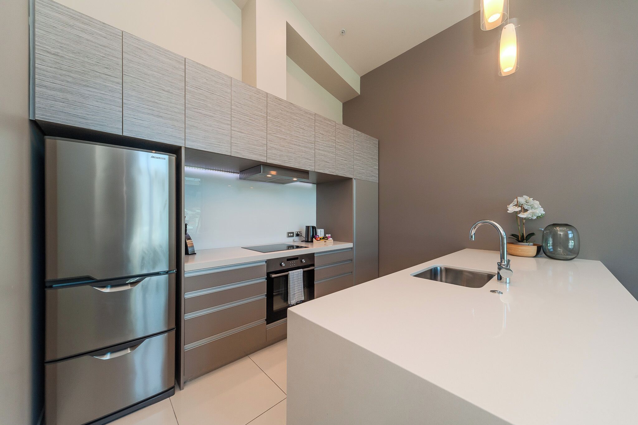 A modern kitchen with stainless steel appliances, a large island with a sink, and a built-in oven.