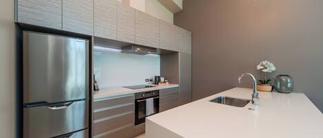 A modern kitchen with stainless steel appliances, a large island with a sink, and a built-in oven.