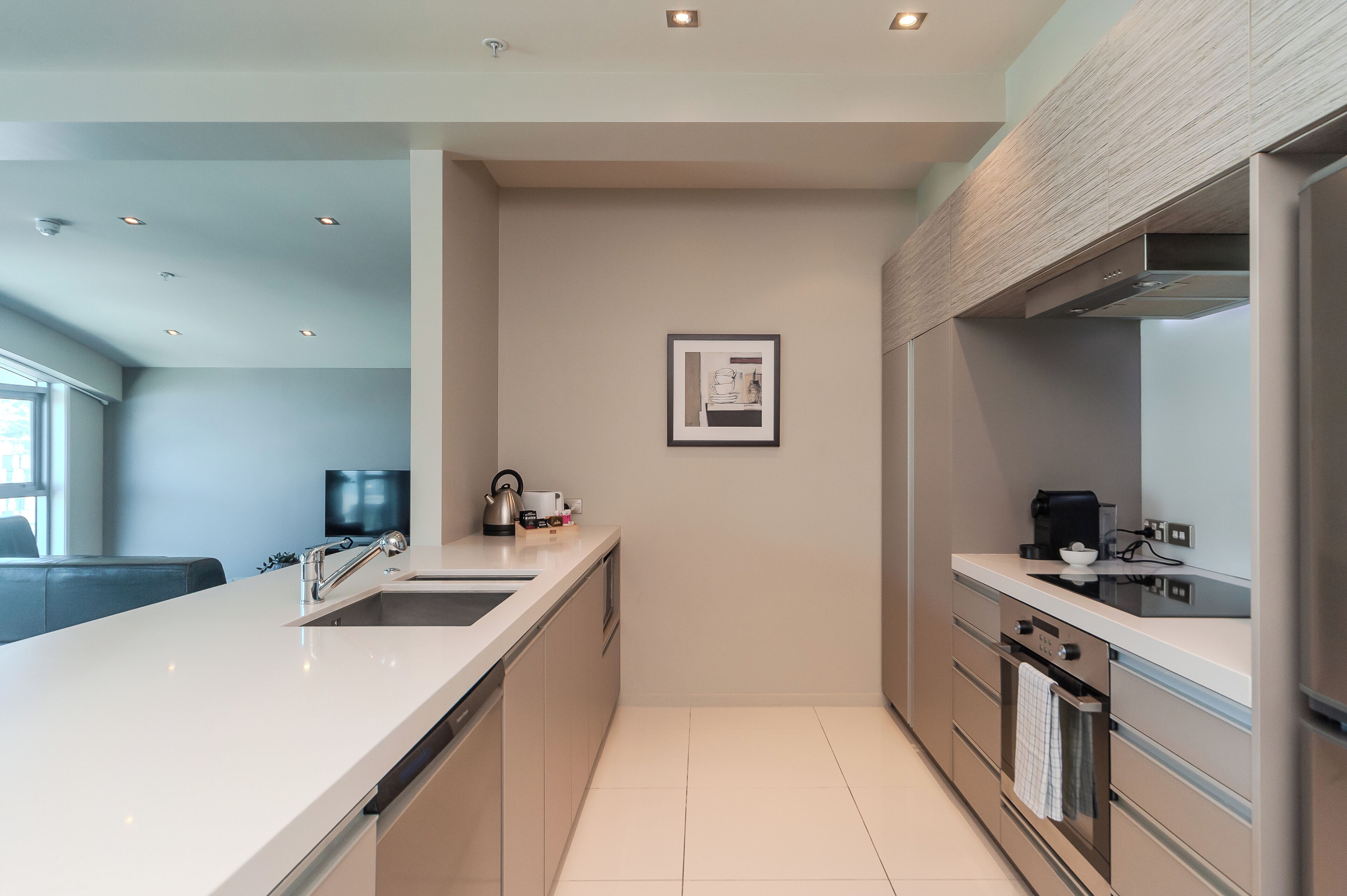 A modern kitchen with a white countertop, stainless steel appliances, and a framed picture on the wall.